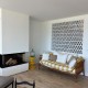 Ambiance cosy et chaleureuse dans ce salon, parquet au sol, cheminée, claustra Montgri émaillé blanc et banquette.