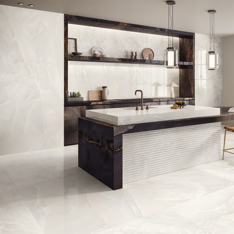 Carrelage effet onyx ivoire Tele di Marmo Onyx Ivory au sol et au mur dans une cuisine moderne avec îlot central en marbre foncé