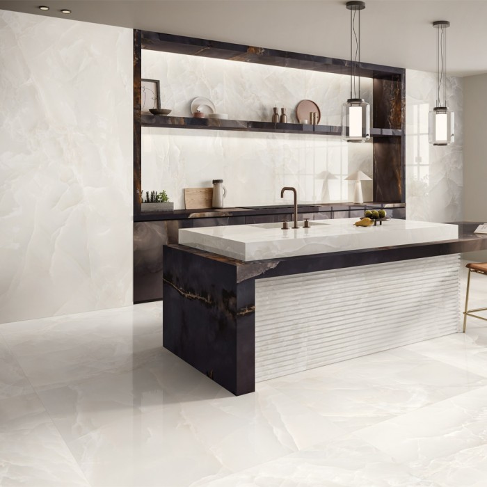 Carrelage effet onyx ivoire Tele di Marmo Onyx Ivory au sol et au mur dans une cuisine moderne avec îlot central en marbre foncé