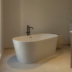 Salle de bain moderne avec baignoire îlot et sol en carrelage pierre de Bourgogne blanc effet mat