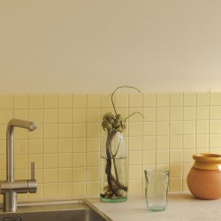 Carrelage uni jaune clair mat Banana 10x10 cm sur trame, posé en crédence de cuisine pour une ambiance lumineuse et rétro