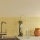 Carrelage uni jaune clair mat Banana 10x10 cm sur trame, posé en crédence de cuisine pour une ambiance lumineuse et rétro