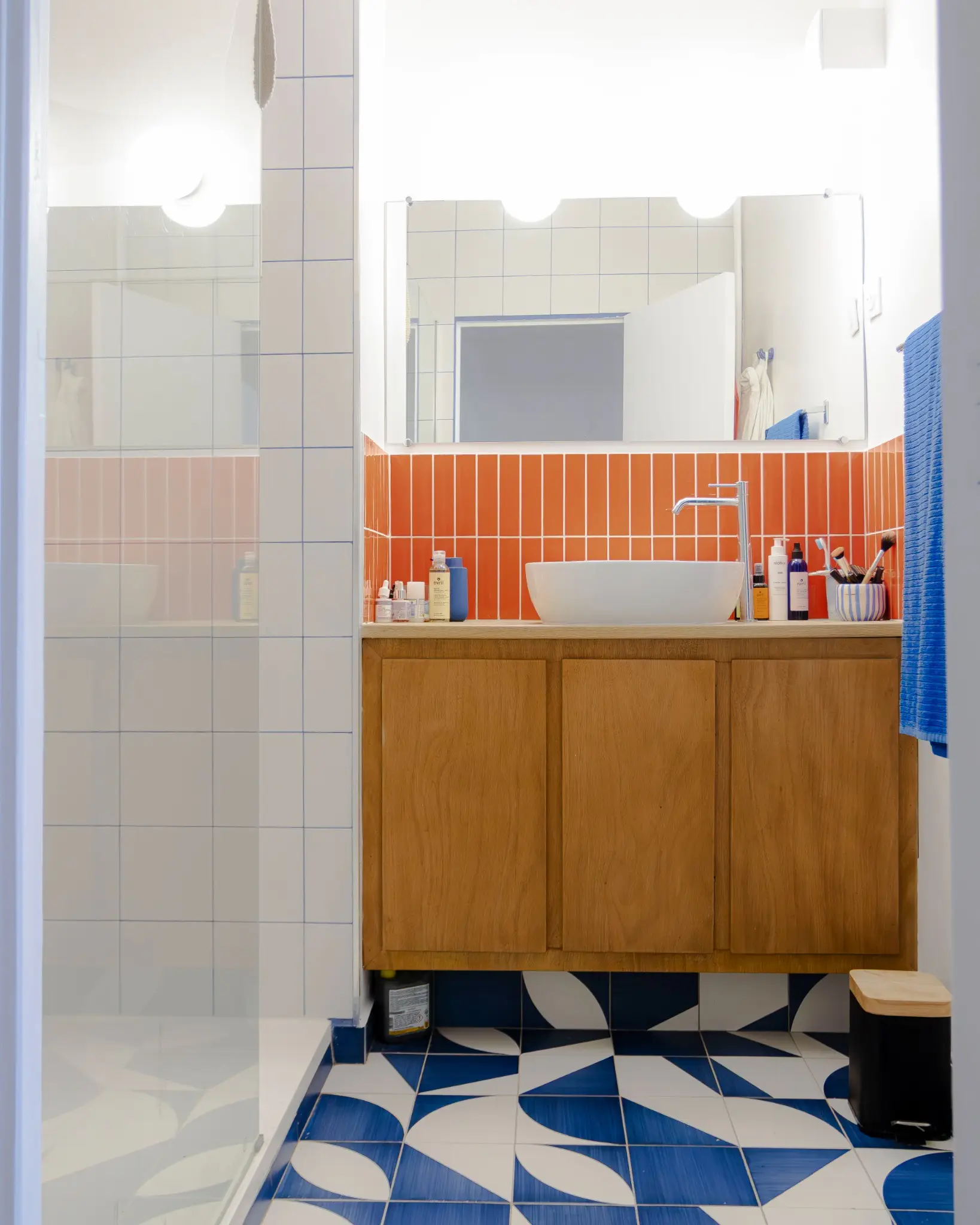 Salle de bain : sol à motifs graphiques bleus et blancs, faïence orange et blanche